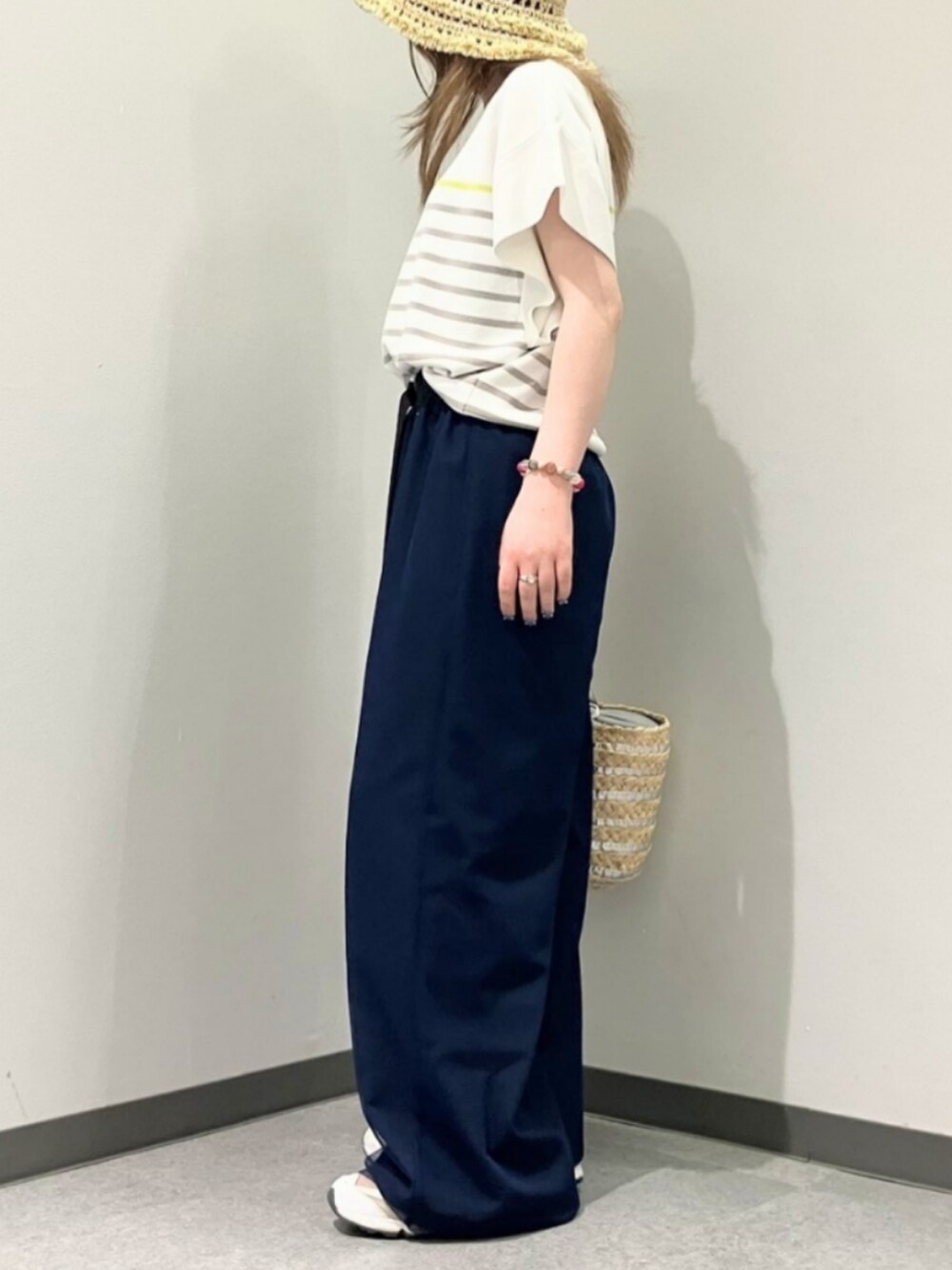 ブルー系のその他パンツ、ホワイト系のニット/セーター、シルバー系のかごバッグを着用したレディースの春コーディネートの2枚目の写真