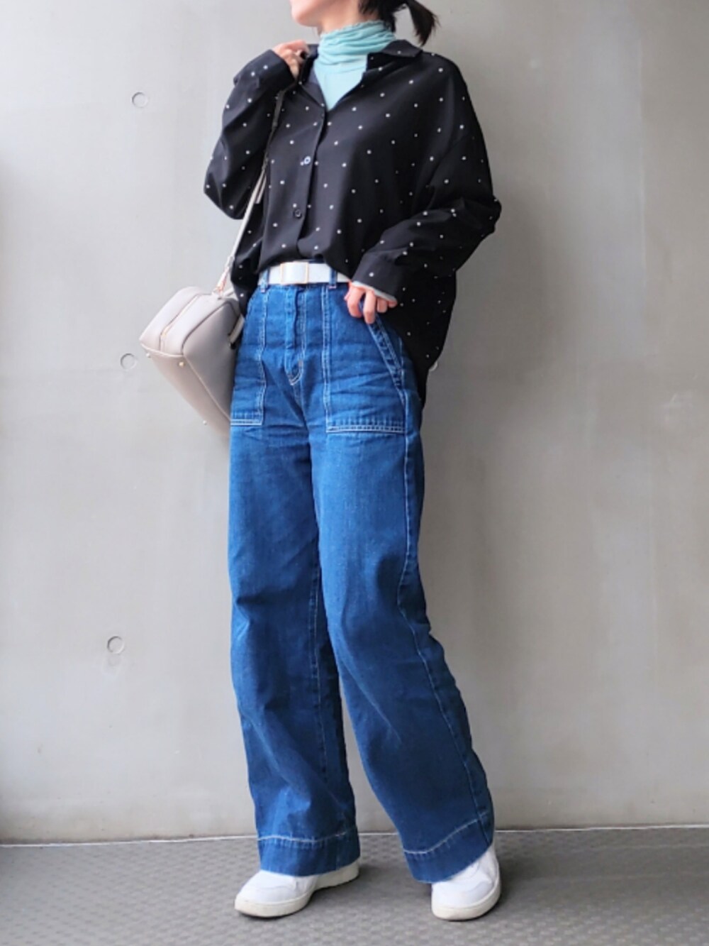 ブルー系のデニムパンツ、ホワイト系のスニーカー、ホワイト系のボストンバッグを着用したレディースの秋コーディネートの2枚目の写真