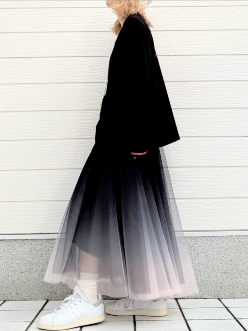 ブラック系のTシャツ/カットソー、ブラック系のスカート、ホワイト系のスニーカーを着用したレディースの秋コーディネートの2枚目の写真