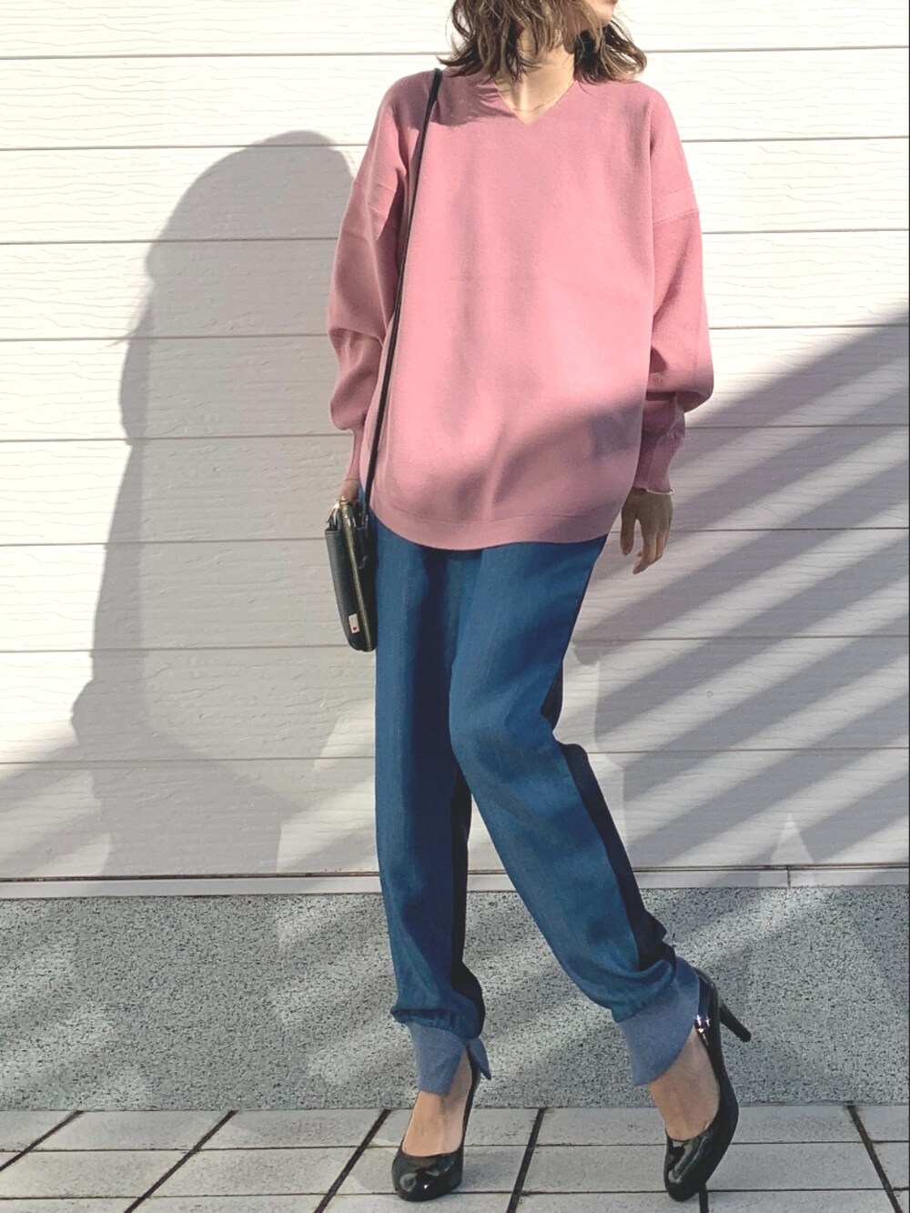ブルー系のデニムパンツ、ブラック系のショルダーバッグ、ピンク系のニット/セーターを着用したレディースの冬コーディネートの4枚目の写真