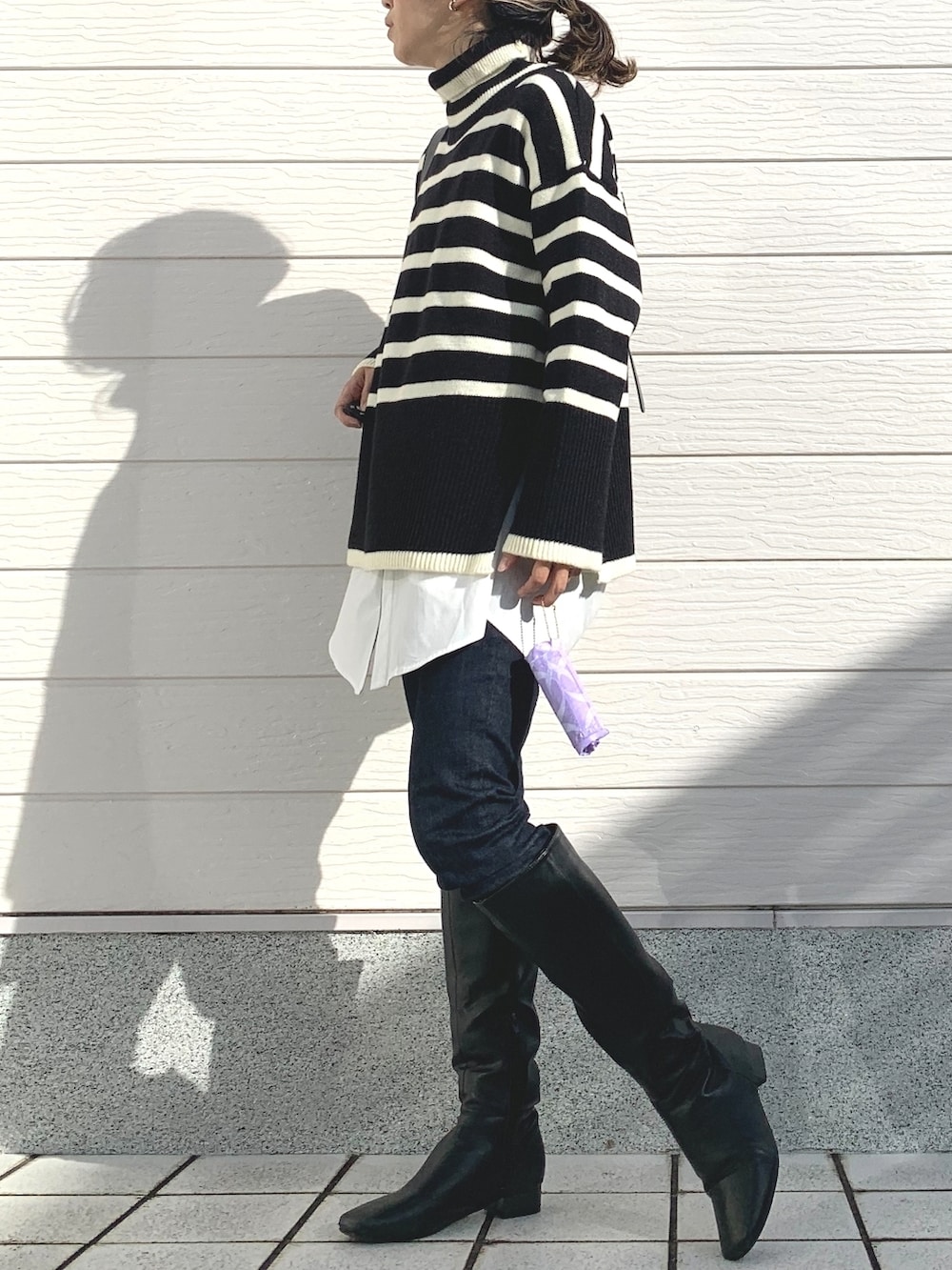 ブラック系のブーツ、ブルー系のデニムパンツ、ホワイト系のシャツ/ブラウスを着用したレディースの冬コーディネートの2枚目の写真