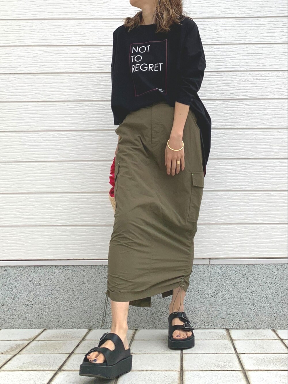 ピンク系のかごバッグ、グリーン系のスカート、ブラック系のサンダルを着用したレディースの春コーディネートの2枚目の写真