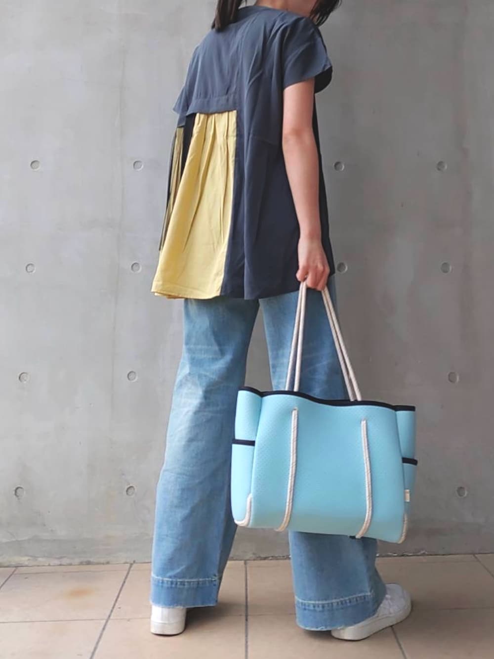 ブルー系のデニムパンツ、ブルー系のトートバッグ、ホワイト系のスニーカーを着用したレディースの春コーディネートの2枚目の写真