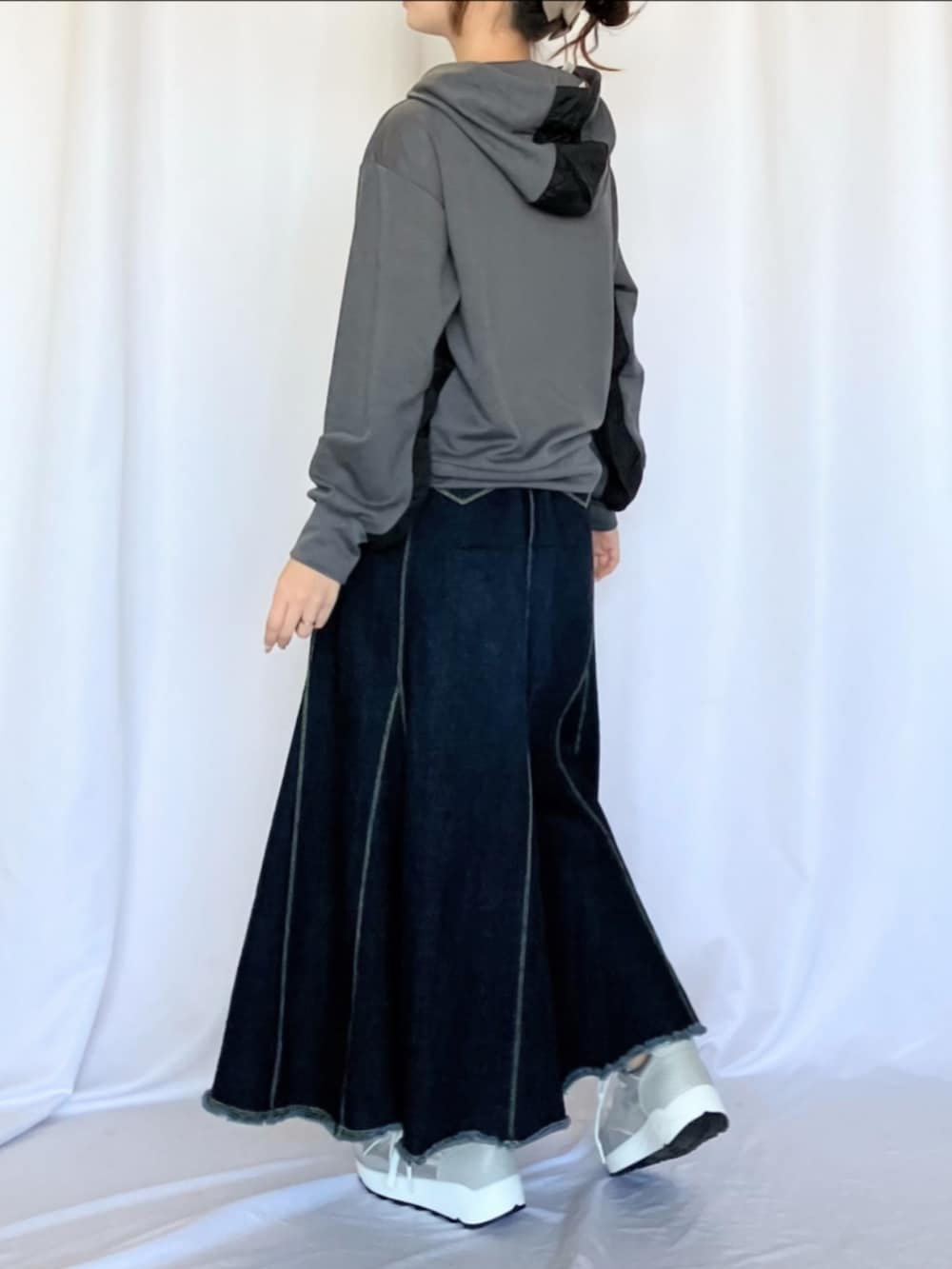 シルバー系のスニーカー、ブルー系のデニムスカート、グレー系のパーカーを着用したレディースの冬コーディネートの3枚目の写真