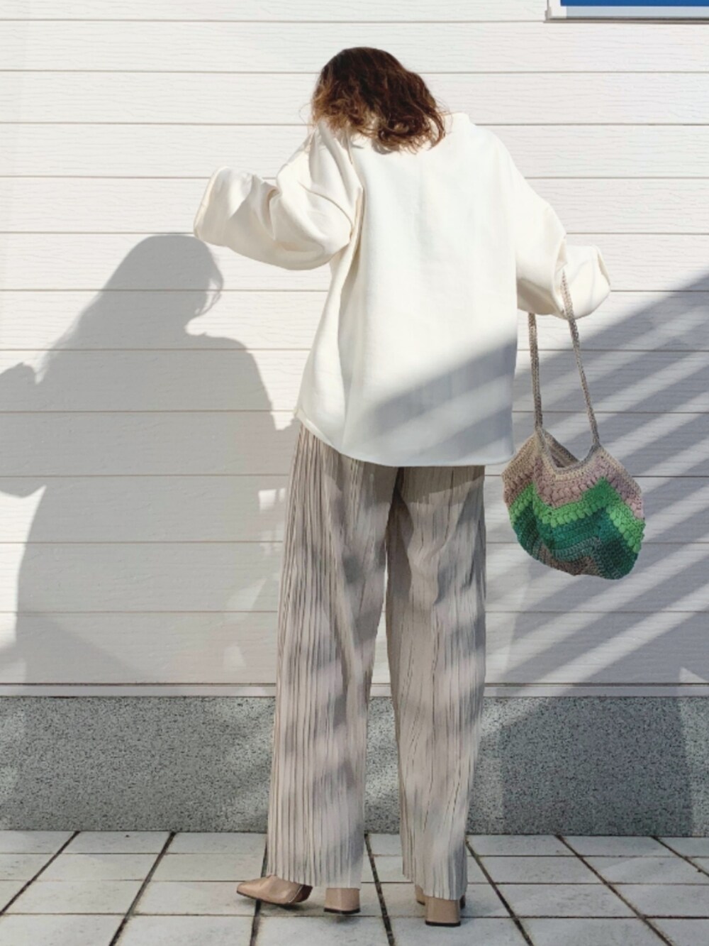 ベージュ系のその他パンツ、ホワイト系のスウェット、グリーン系のハンドバッグを着用したレディースの冬コーディネートの3枚目の写真