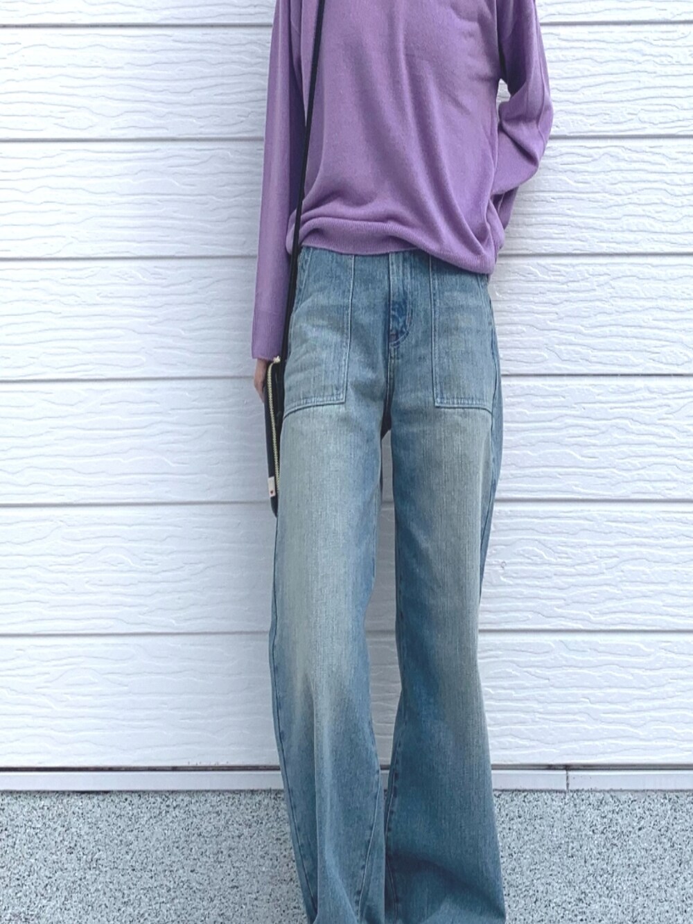 ブラック系のスニーカー、ブラック系のショルダーバッグ、ブルー系のデニムパンツを着用したレディースの冬コーディネートの2枚目の写真