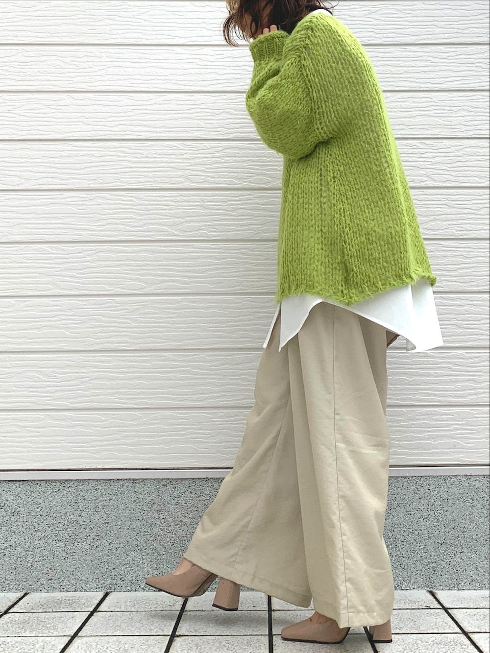 グリーン系のニット/セーター、ホワイト系のシャツ/ブラウス、ベージュ系のショルダーバッグを着用したレディースの冬コーディネートの3枚目の写真