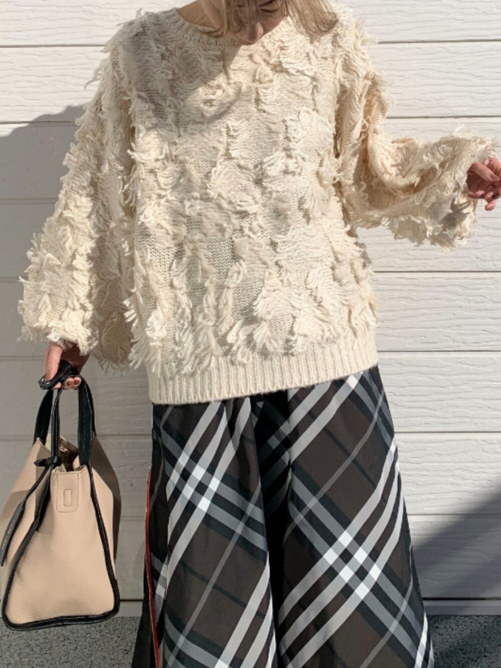 ホワイト系のニット/セーター、ベージュ系のトートバッグ、ブラウン系のスカートを着用したレディースの秋コーディネートの4枚目の写真