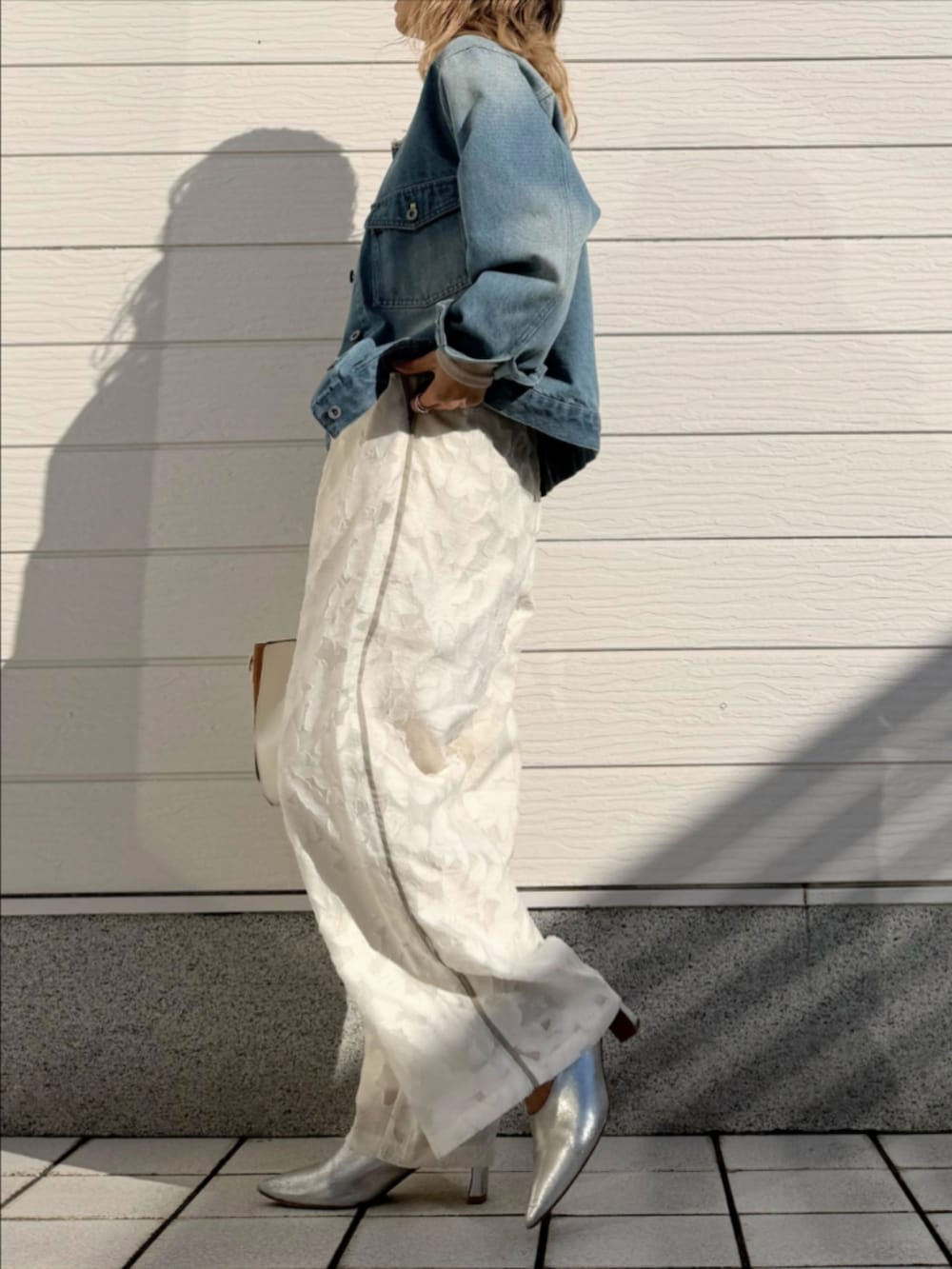 ブルー系のデニムジャケット、ホワイト系のトートバッグ、ホワイト系のTシャツ/カットソーを着用したレディースの冬コーディネートの2枚目の写真