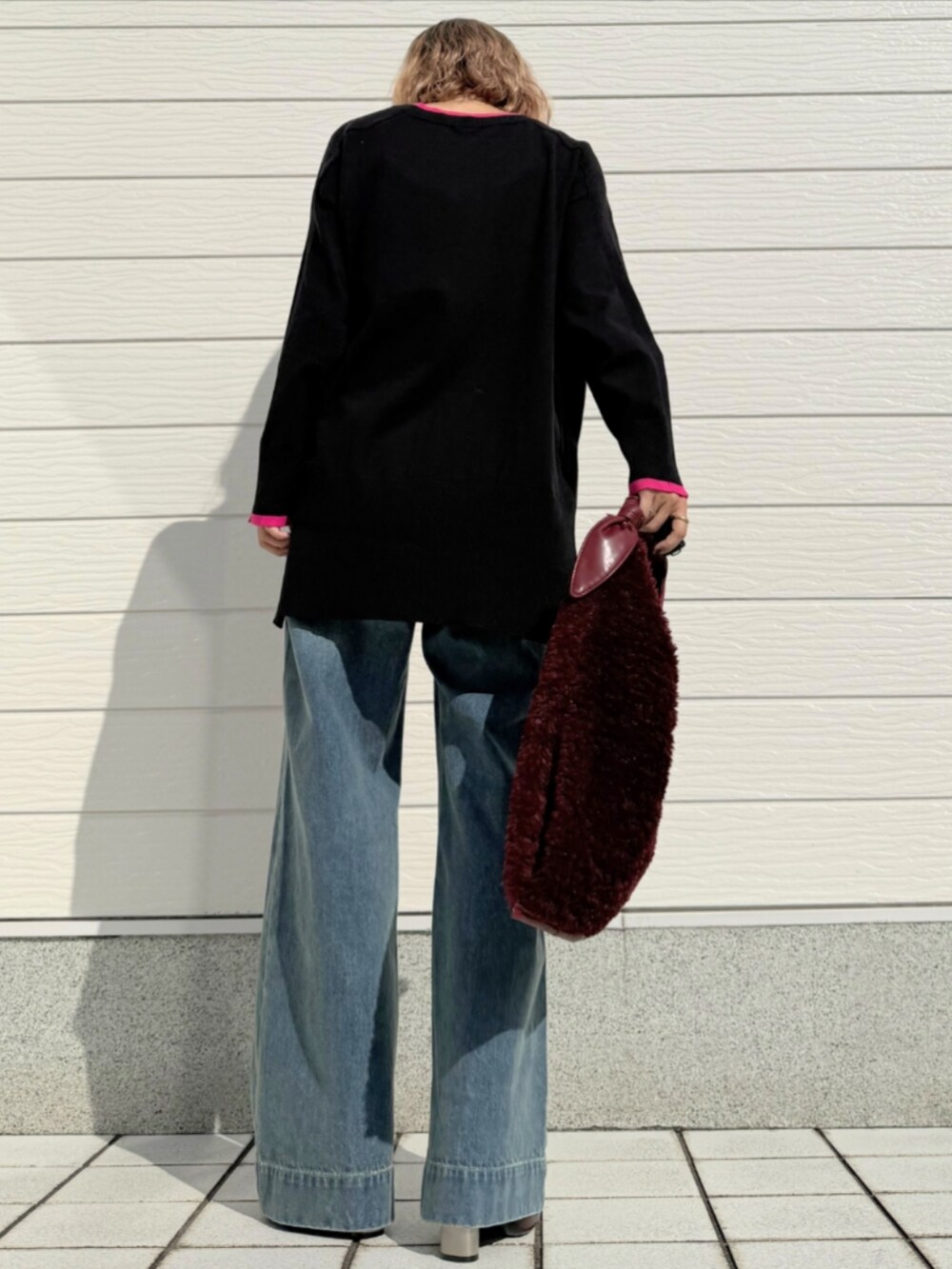 レッド系のトートバッグ、ブルー系のデニムパンツ、ブラック系のニット/セーターを着用したレディースの秋コーディネートの3枚目の写真