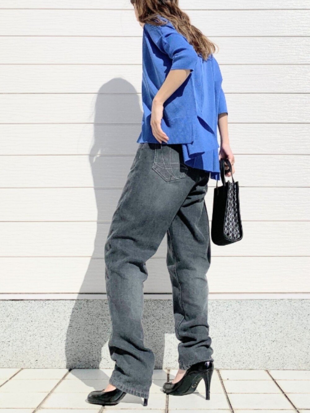 グレー系のデニムパンツ、ブラック系のショルダーバッグ、ブルー系のカーディガン/ボレロを着用したレディースの春コーディネートの3枚目の写真