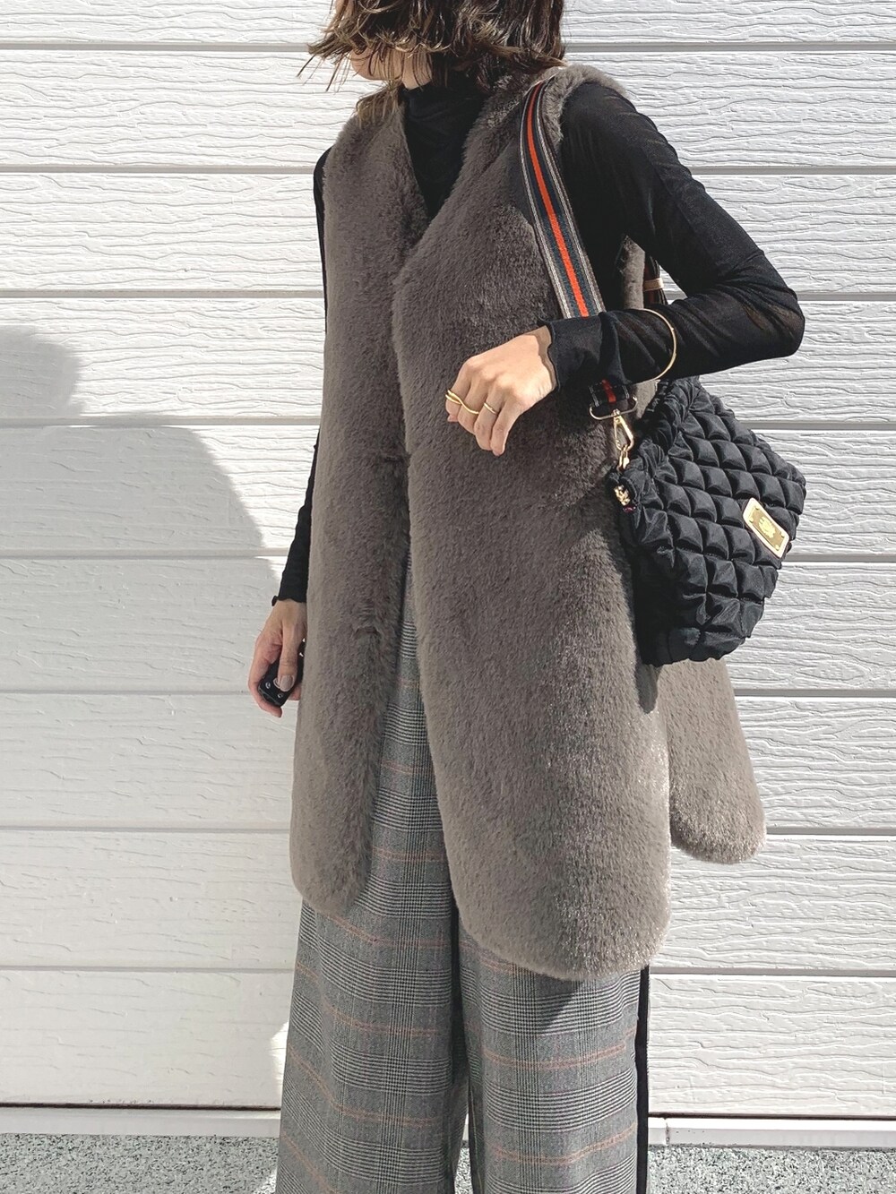 ブラック系のショルダーバッグ、ブラウン系のベスト、ブラック系のTシャツ/カットソーを着用したレディースの秋コーディネートの3枚目の写真