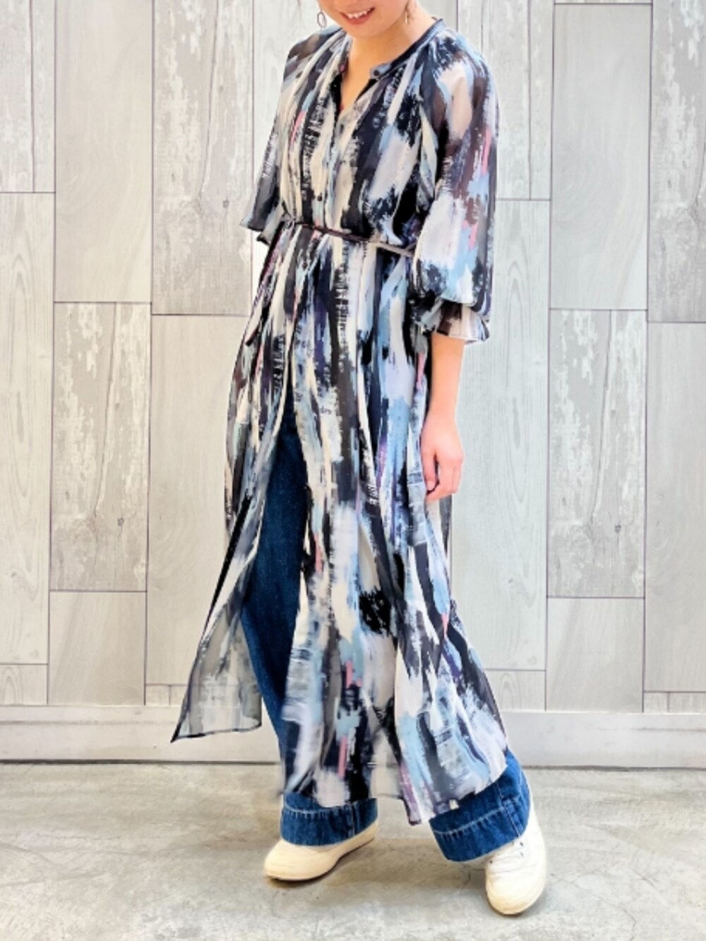 ブルー系のデニムパンツ、ブラック系のワンピースを着用したレディースの春コーディネートの2枚目の写真