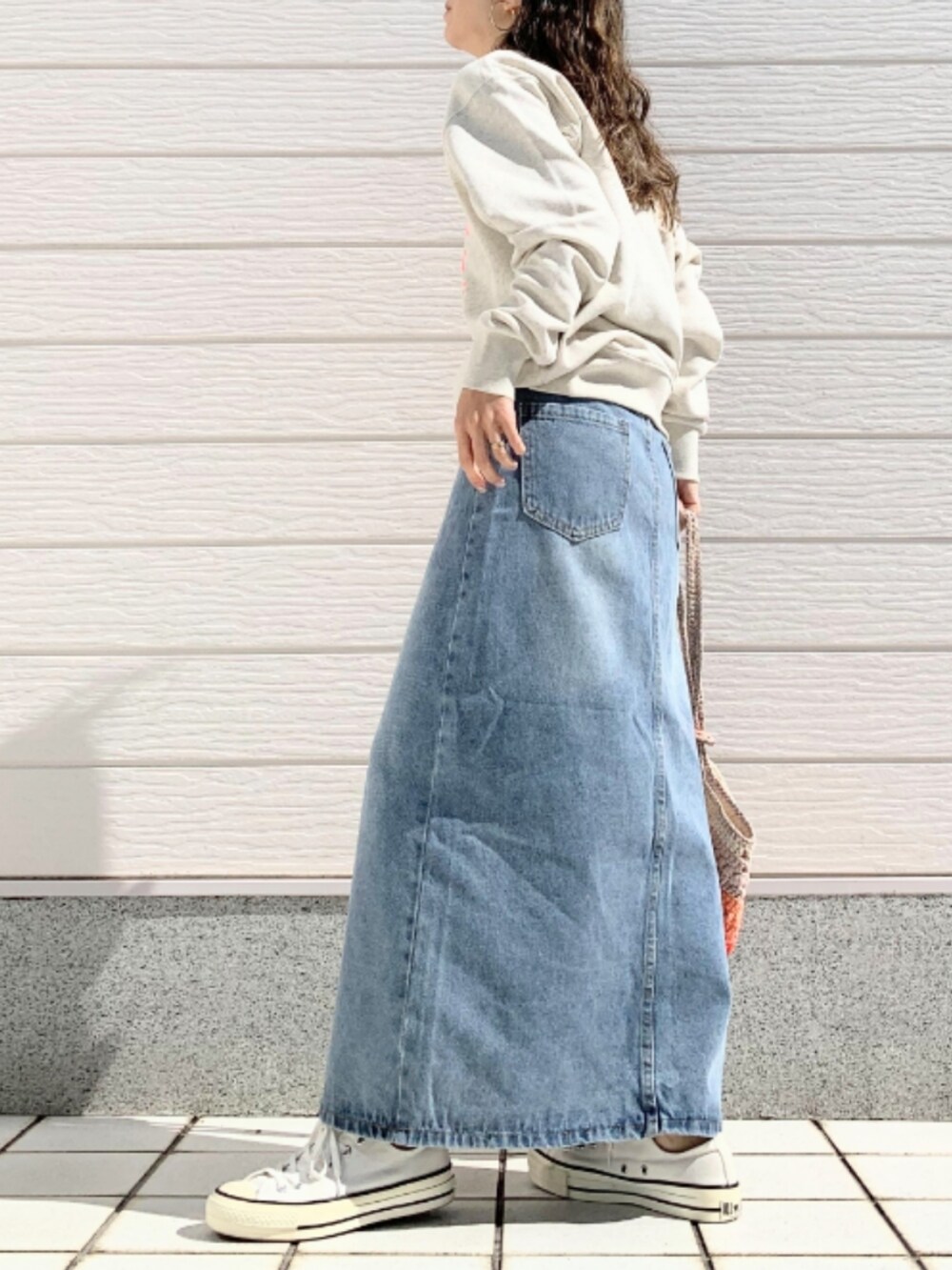 ベージュ系のスウェット、ブルー系のデニムスカート、ホワイト系のスニーカーを着用したレディースの春コーディネートの2枚目の写真