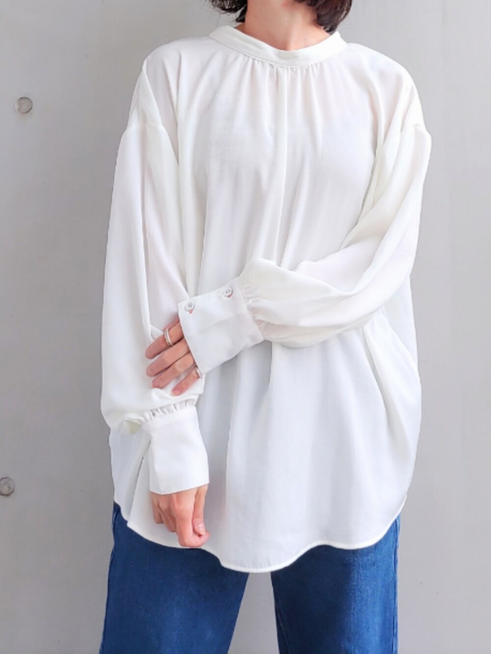 ブルー系のデニムパンツ、ホワイト系のスニーカー、ブラック系のニット/セーターを着用したレディースの秋コーディネートの5枚目の写真