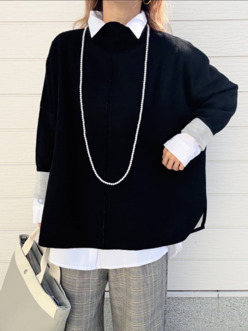 グレー系のトートバッグ、ホワイト系のシャツ/ブラウス、ブラック系のニット/セーターを着用したレディースの冬コーディネートの3枚目の写真