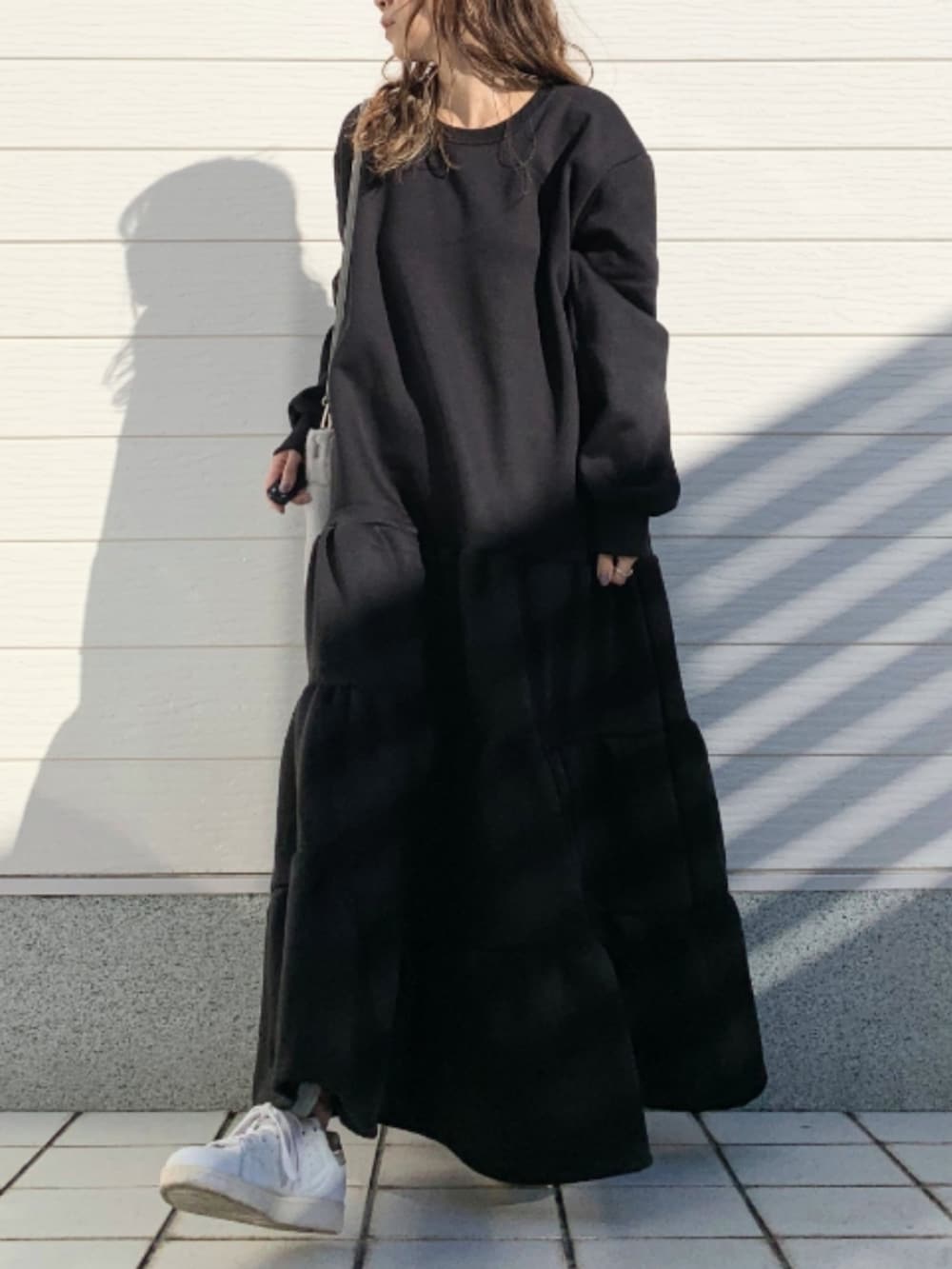 グレー系のショルダーバッグ、ホワイト系のスニーカー、ブラック系のワンピースを着用したレディースの冬コーディネートの2枚目の写真