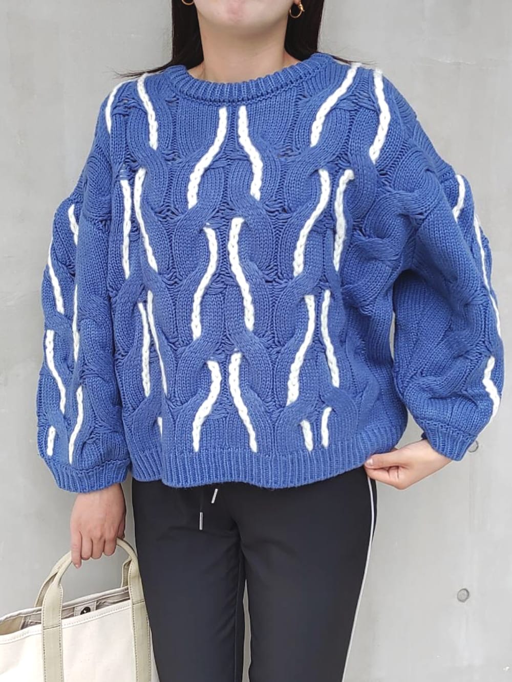 ブラック系のその他パンツ、ブルー系のニット/セーター、ベージュ系のトートバッグを着用したレディースの秋コーディネートの4枚目の写真