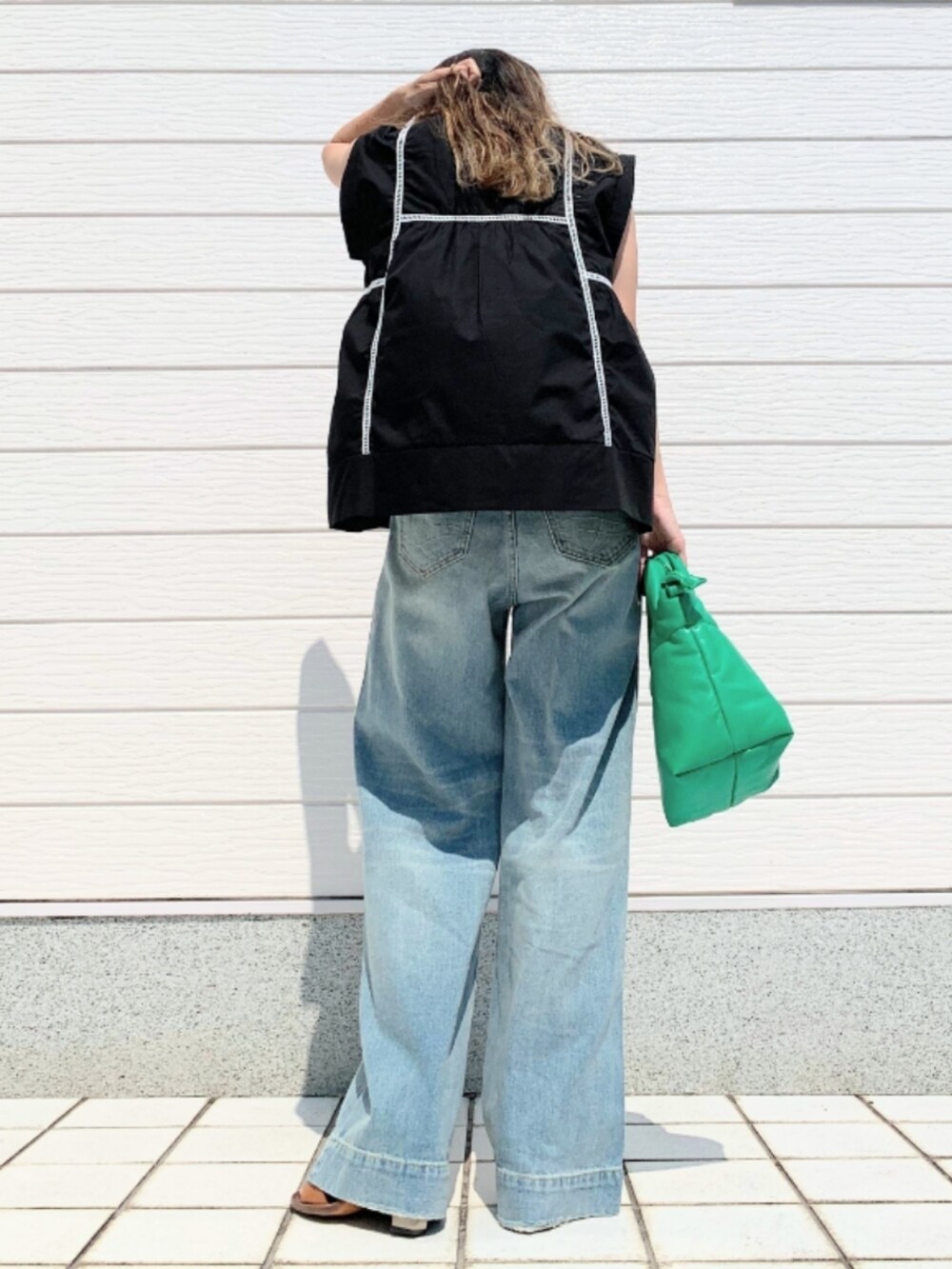 ブルー系のデニムパンツ、グリーン系のショルダーバッグ、ブラック系のシャツ/ブラウスを着用したレディースの夏コーディネートの3枚目の写真