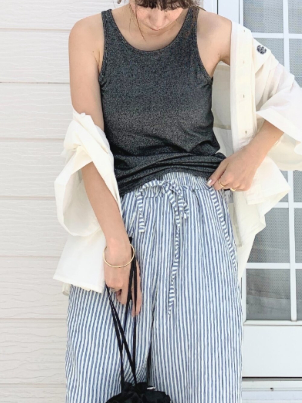 ブラック系のクラッチバッグ、ブラック系のタンクトップ、ホワイト系のシャツ/ブラウスを着用したレディースの夏コーディネートの5枚目の写真