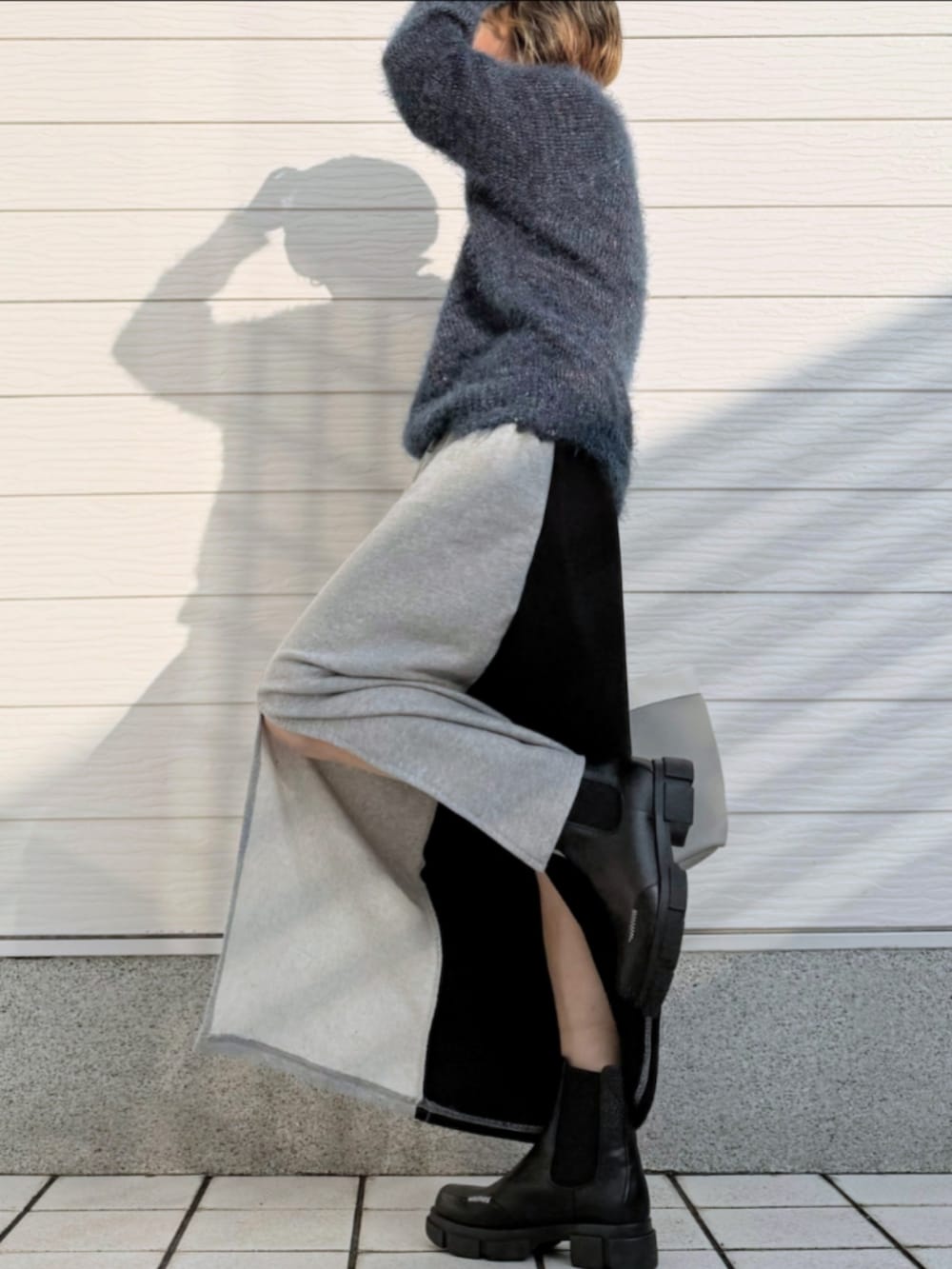 グレー系のトートバッグ、ブラック系のブーツ、グレー系のスカートを着用したレディースの秋コーディネートの2枚目の写真
