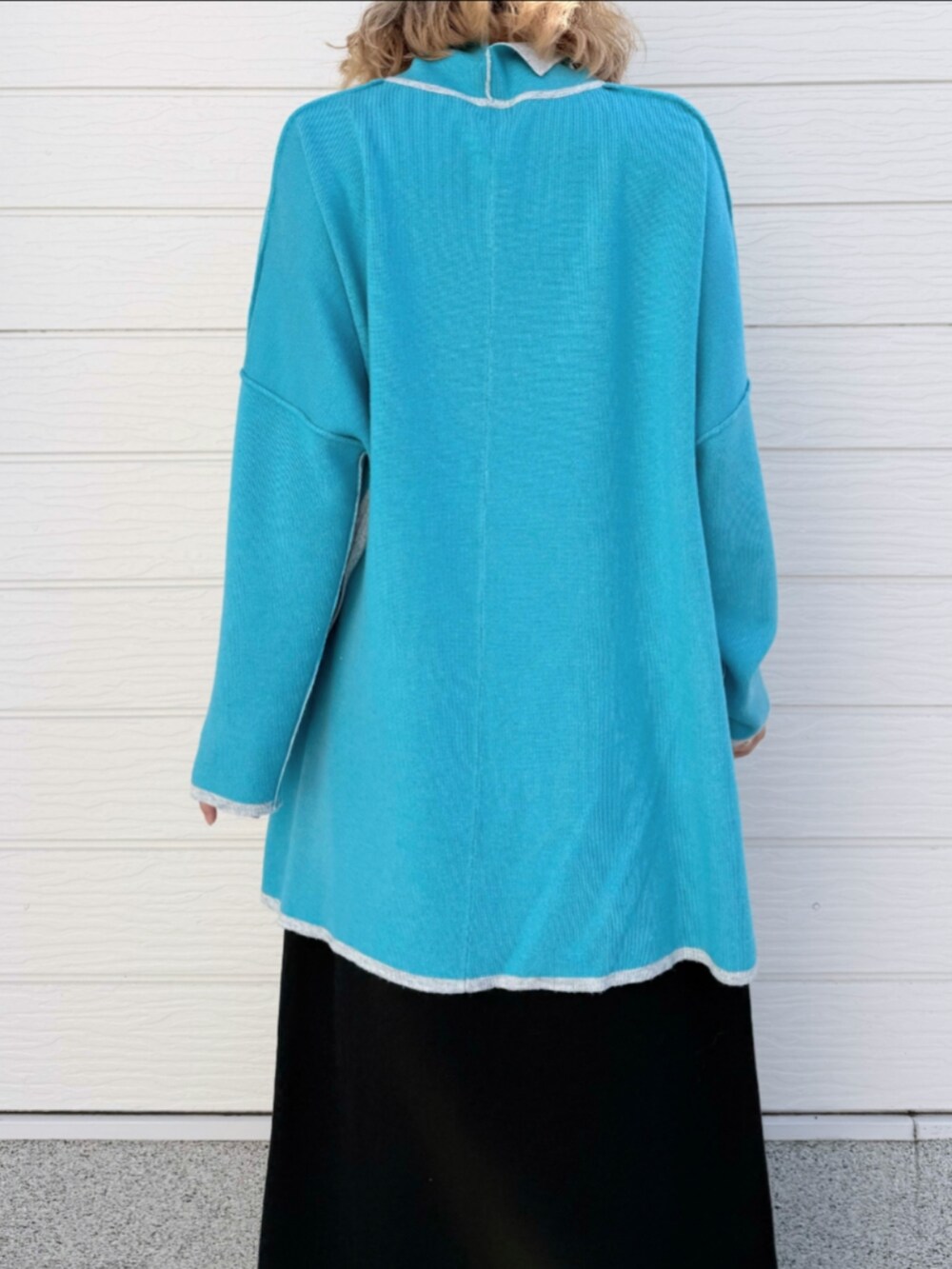 グレー系のニット/セーター、グレー系のスカート、ブラック系のキャップを着用したレディースの秋コーディネートの5枚目の写真