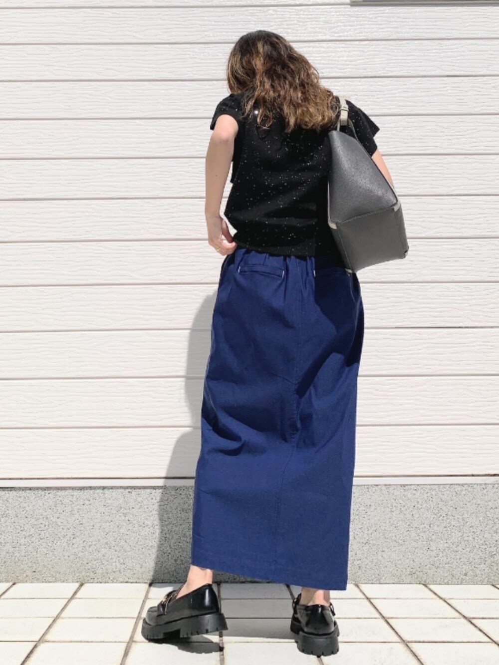 ブルー系のスカート、ブラック系のローファー、グレー系のトートバッグを着用したレディースの春コーディネートの3枚目の写真