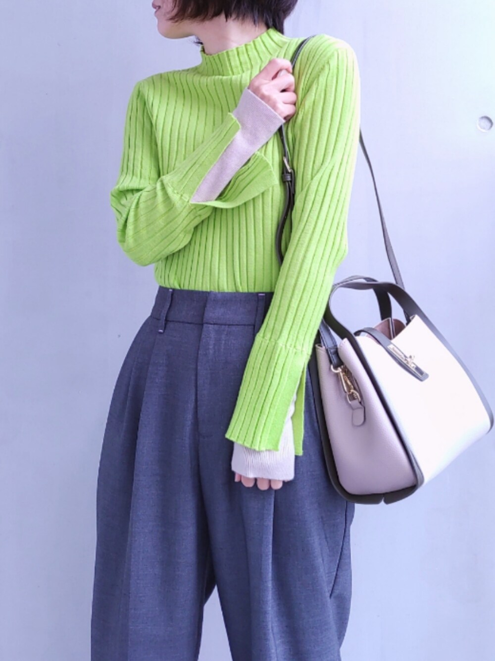 グレー系のスラックス、ホワイト系のトートバッグ、グリーン系のニット/セーターを着用したレディースの冬コーディネートの4枚目の写真
