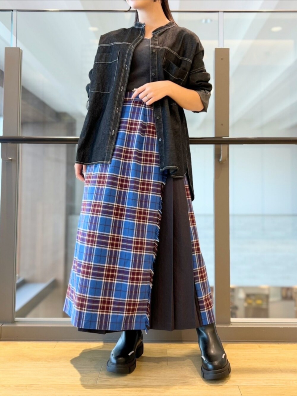 ブラック系のブーツ、ブルー系のスカート、ブラック系のシャツ/ブラウスを着用したレディースの秋コーディネートの2枚目の写真