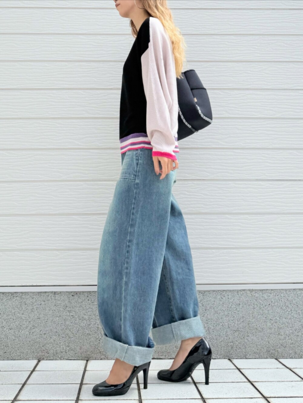 ブルー系のデニムパンツ、ブラック系のニット/セーター、ブルー系のトートバッグを着用したレディースの秋コーディネートの2枚目の写真