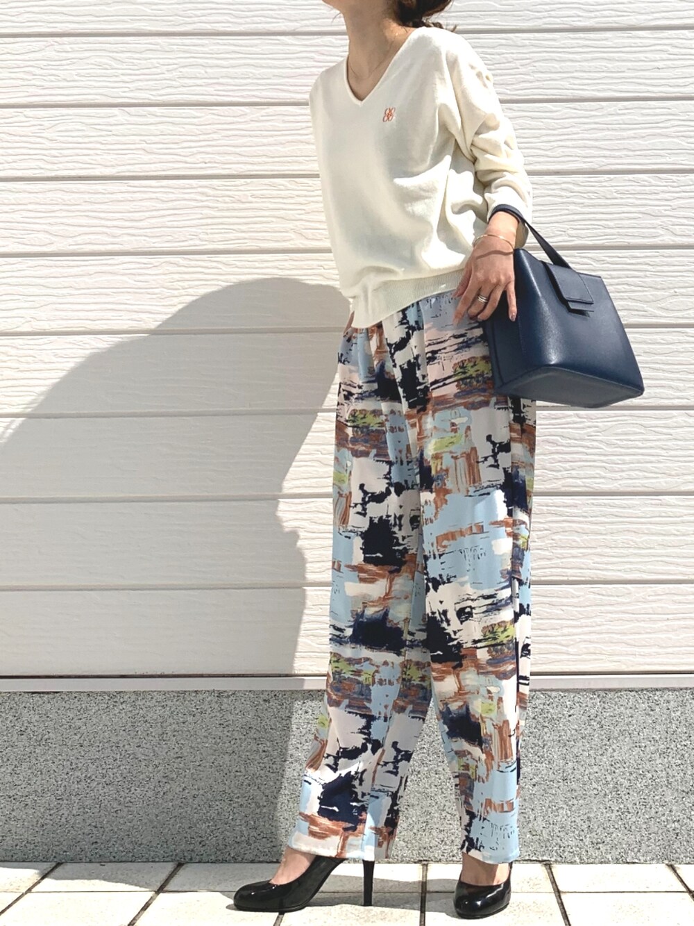 ブルー系のハンドバッグ、ホワイト系のニット/セーター、ブルー系のその他パンツを着用したレディースの春コーディネートの2枚目の写真