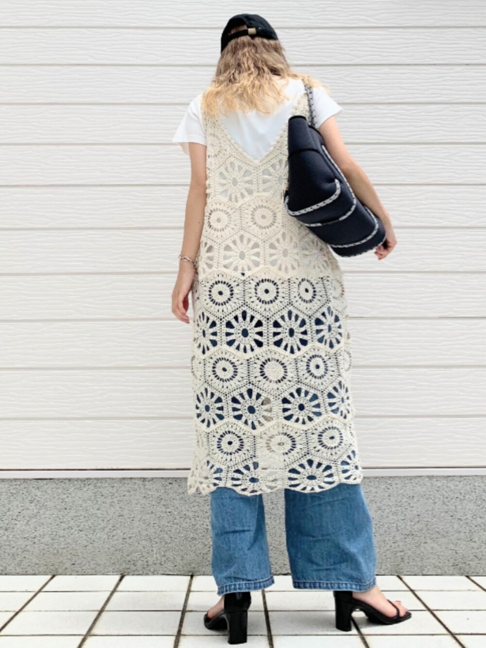 ブルー系のデニムパンツ、ブルー系のトートバッグ、ホワイト系のワンピースを着用したレディースの夏コーディネートの3枚目の写真