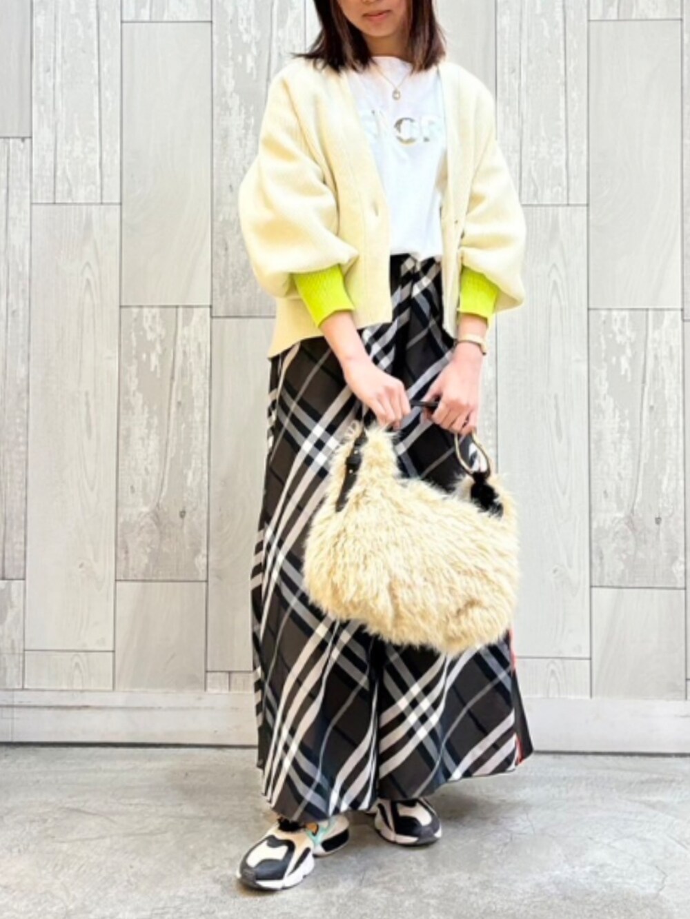 ベージュ系のハンドバッグ、ブラウン系のスカート、ホワイト系のカーディガン/ボレロを着用したレディースの冬コーディネートの2枚目の写真