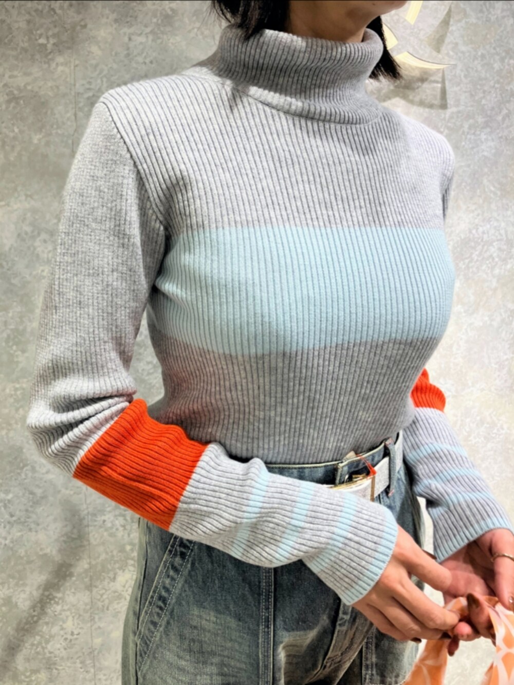 オレンジ系のエコバッグ/サブバッグ、ブルー系のデニムパンツ、グレー系のニット/セーターを着用したレディースの秋コーディネートの5枚目の写真