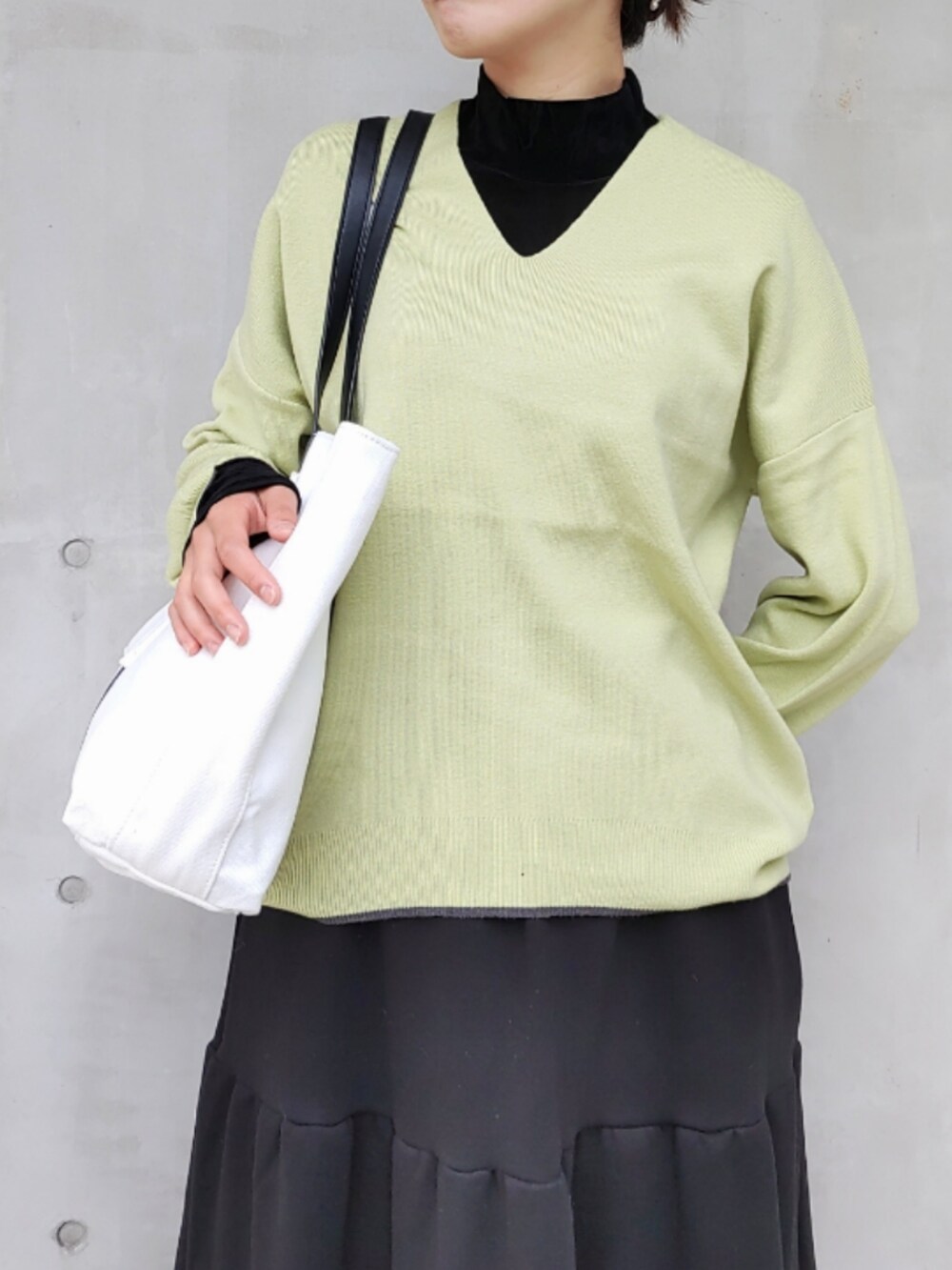 ブラック系のスカート、ブラック系のスニーカー、グリーン系のニット/セーターを着用したレディースの秋コーディネートの3枚目の写真