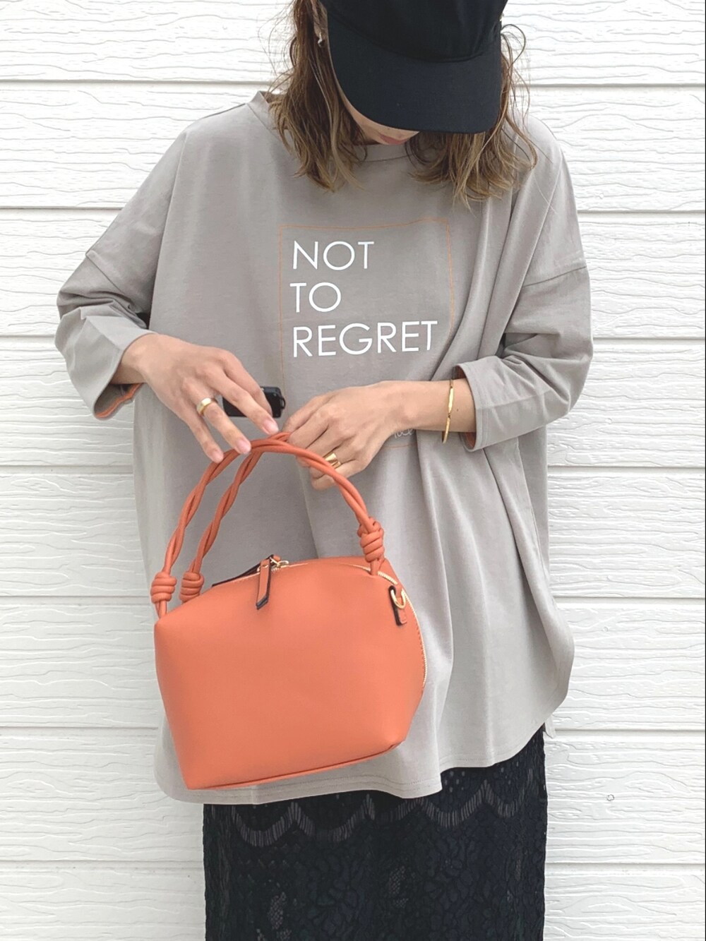 オレンジ系のハンドバッグ、ベージュ系のTシャツ/カットソー、ブラック系のスカートを着用したレディースの春コーディネートの4枚目の写真
