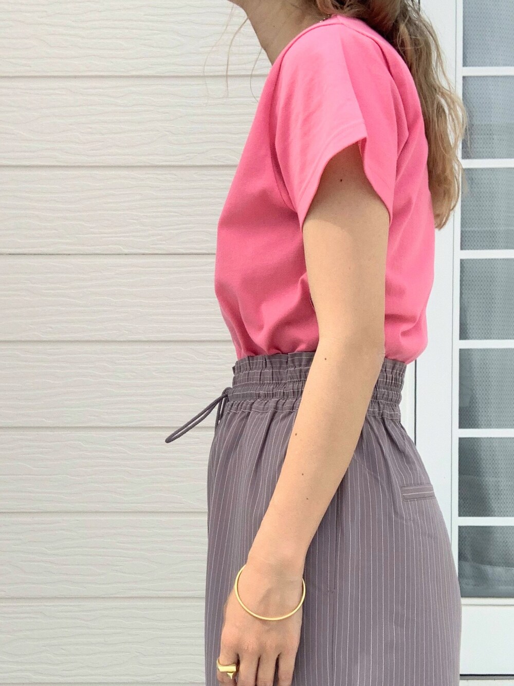 ピンク系のTシャツ/カットソー、グレー系のスラックス、ホワイト系のキャップを着用したレディースの春コーディネートの4枚目の写真