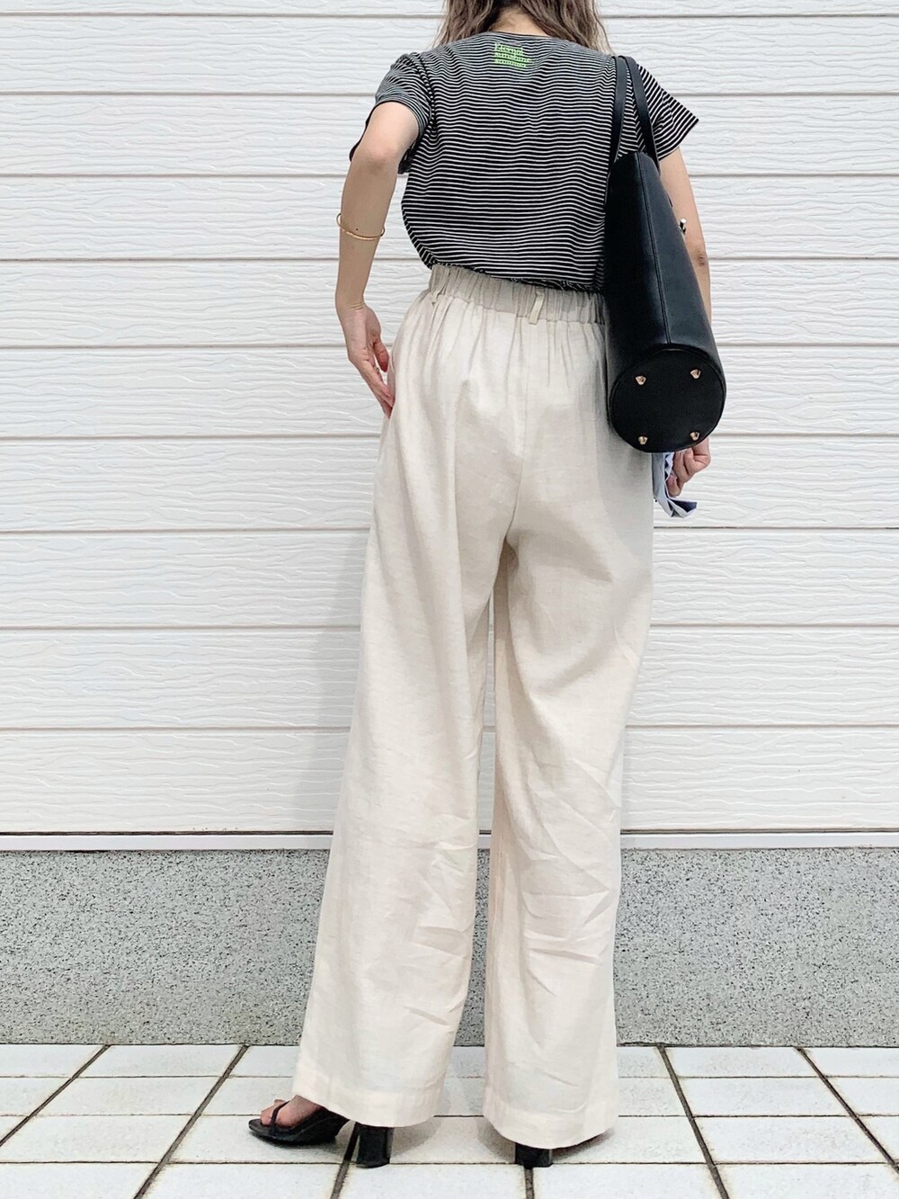 ブラック系のTシャツ/カットソー、ホワイト系のその他パンツ、ブラック系のトートバッグを着用したレディースの春コーディネートの3枚目の写真