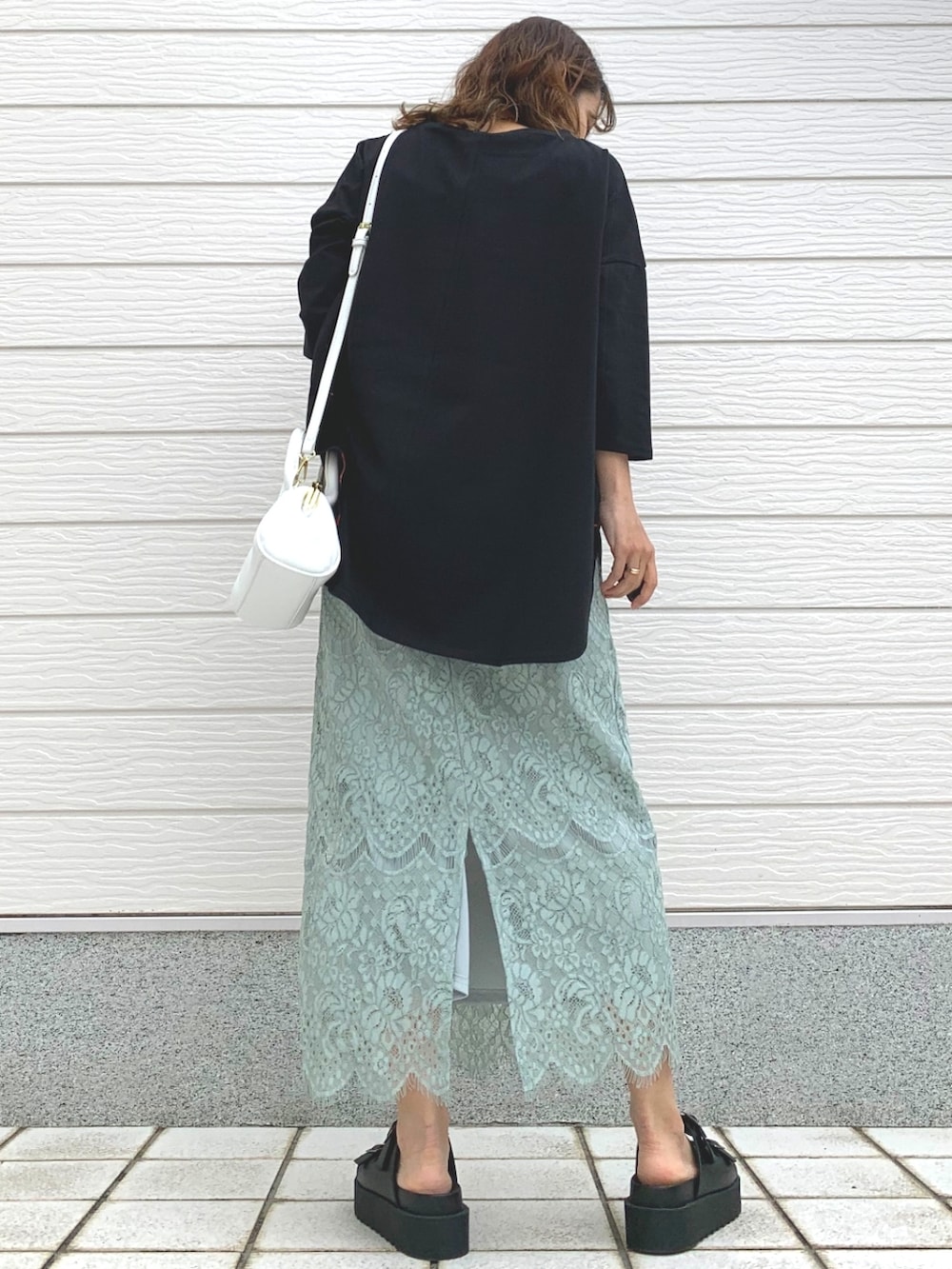 グリーン系のスカート、ブラック系のサンダル、ブラック系のTシャツ/カットソーを着用したレディースの春コーディネートの3枚目の写真