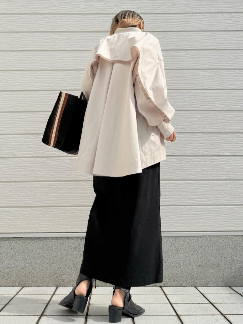 ブラック系のトートバッグ、ブラック系のサンダル、ブラック系のスカートを着用したレディースの冬コーディネートの2枚目の写真