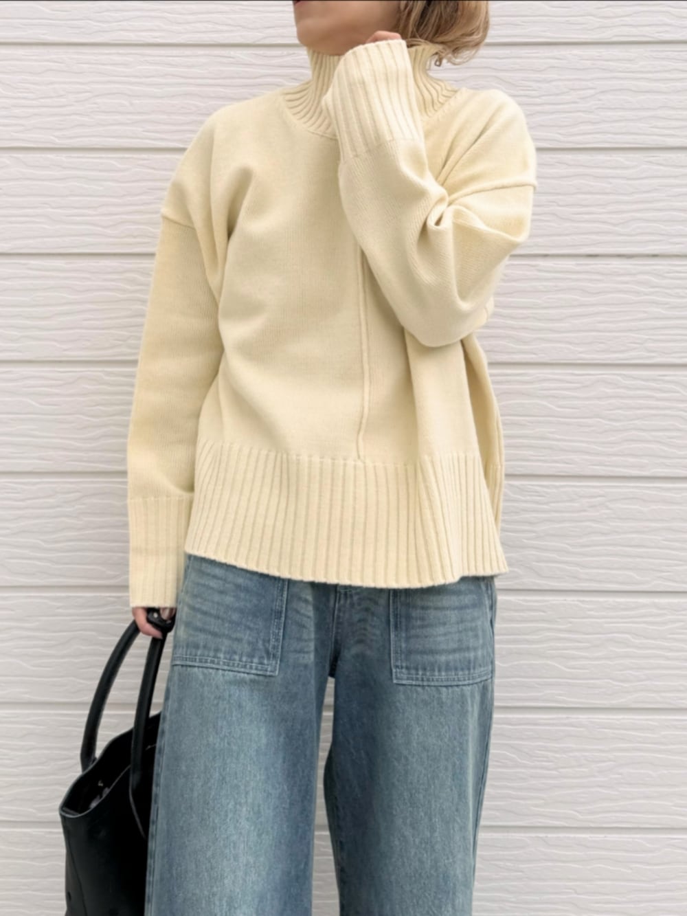 ブルー系のデニムパンツ、ブラック系のトートバッグ、ホワイト系のニット/セーターを着用したレディースの冬コーディネートの4枚目の写真