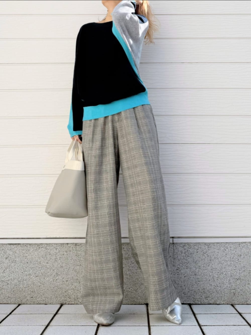 グレー系のトートバッグ、ブルー系のニット/セーター、ベージュ系のスラックスを着用したレディースの冬コーディネートの2枚目の写真