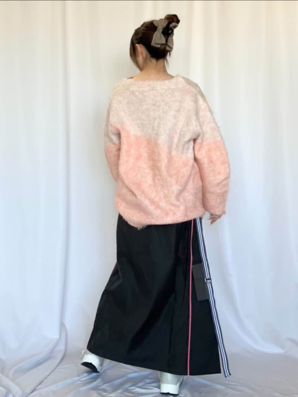 ブラック系のデニムスカート、シルバー系のスニーカー、ピンク系のカーディガン/ボレロを着用したレディースの冬コーディネートの2枚目の写真