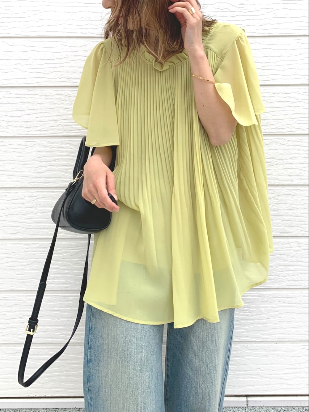 ブラック系のショルダーバッグ、ブルー系のデニムパンツ、ブラック系のサンダルを着用したレディースの春コーディネートの3枚目の写真