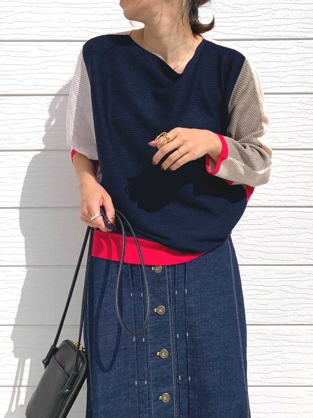 ブルー系のデニムスカート、ブラック系のスニーカー、ブラック系のショルダーバッグを着用したレディースの秋コーディネートの3枚目の写真