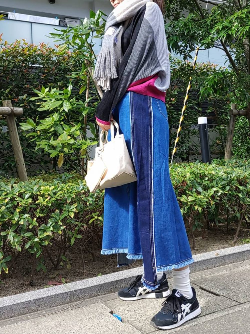 ベージュ系のトートバッグ、ブラック系のニット/セーター、ブラック系のスニーカーを着用したレディースの秋コーディネートの2枚目の写真