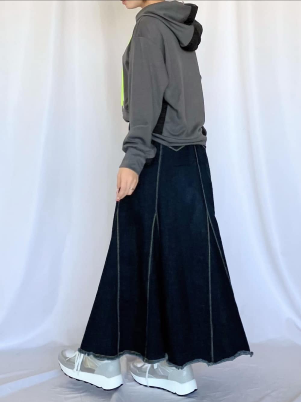 シルバー系のスニーカー、ブルー系のデニムスカート、グレー系のパーカーを着用したレディースの冬コーディネートの2枚目の写真