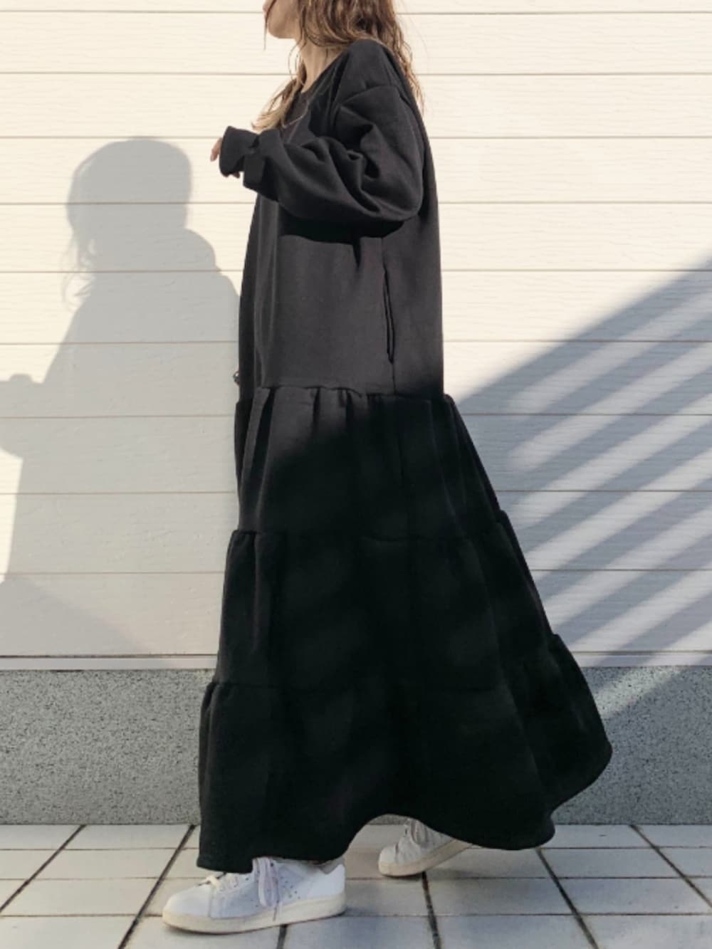 グレー系のショルダーバッグ、ホワイト系のスニーカー、ブラック系のワンピースを着用したレディースの冬コーディネートの3枚目の写真