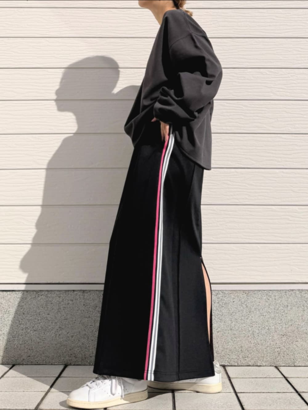 ブラック系のスカート、グレー系のTシャツ/カットソー、ホワイト系のスニーカーを着用したレディースの春コーディネートの2枚目の写真