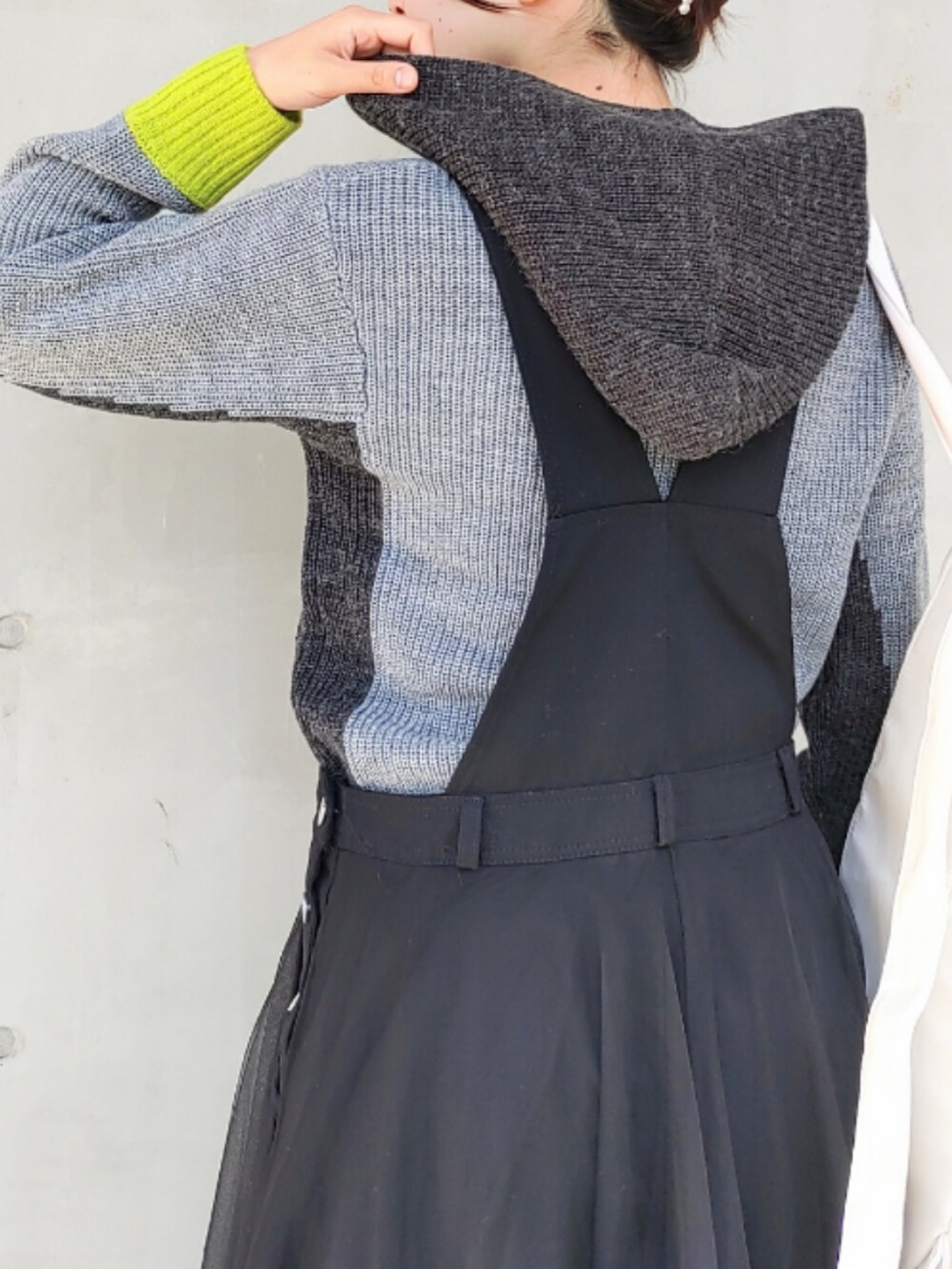 ホワイト系のバックパック/リュック、グレー系のニット/セーター、ブラック系のジャンパースカートを着用したレディースの秋コーディネートの4枚目の写真